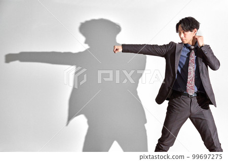 一個穿著西裝擺出戰鬥姿勢的年輕人的商業形象 99697275