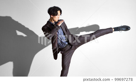 一個穿著西裝的年輕人擺出高踢姿勢的商業形象 99697278