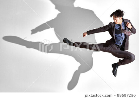 Business image of a young man in a suit doing a flying kick 99697280