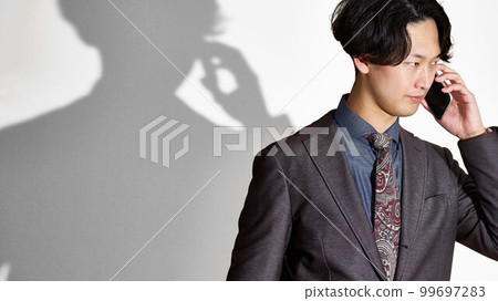 一個穿西裝的年輕人表情嚴肅地打電話 99697283