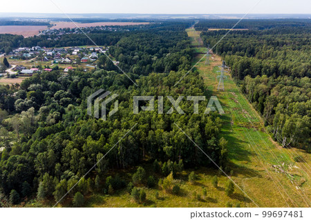 View of a high-voltage power line running through forests and countryside 99697481