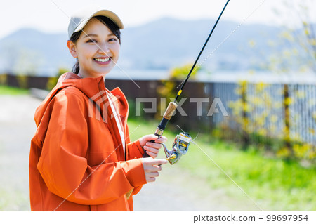 Smiling young woman enjoying hobby fishing 99697954
