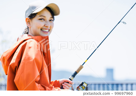 Smiling young woman enjoying hobby fishing 99697960