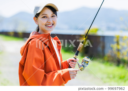 Smiling young woman enjoying hobby fishing 99697962
