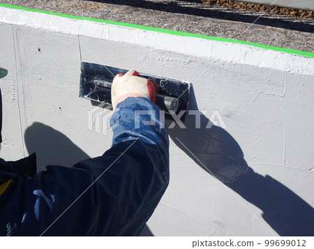 A trowel is being applied to prevent the spalling of a concrete structure 99699012