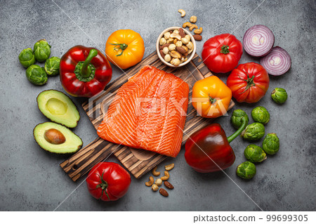 Fresh raw salmon fillet on wooden cutting board, organic bio vegetables and nuts, rustic stone grey background top view. Ingredients full of vitamins for healthy diet and nutrition 99699305