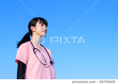 A female nurse wearing a scrub standing against the blue sky, a medical worker, a doctor, an outpatient, an examination, the future, trimming up 99700800