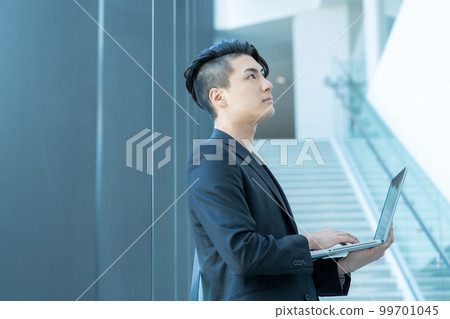 在辦公樓的樓梯上操作個人電腦的年輕商人。攝影合作“LINK FOREST” 在辦公樓的樓梯上操作個人電腦的年輕商人。攝影合作“LINK FOREST” 99701045