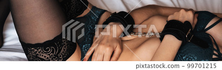 slender body of a young girl in lingerie with stockings with hands in leather handcuffs on the bed slender body of a young girl in lingerie with stockings with hands in leather handcuffs on the bed 99701215