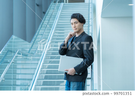 寫字樓樓梯前拿著電腦的年輕商人的肖像。攝影合作“LINK FOREST” 99701351
