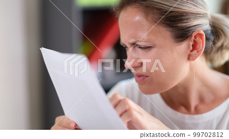 Focused female trying read text, squinting to see more clearly 99702812