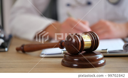 Wooden judge gavel on table doctor doing paperwork on blurred background Wooden judge gavel on table doctor doing paperwork on blurred background 99702842
