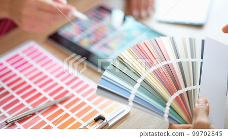 Designer holding fan of colourful paper samples in hand 99702845