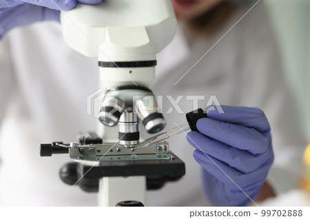 Chemist lab assistant looking at test sample using microscope Chemist lab assistant looking at test sample using microscope 99702888