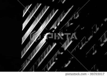 The sun reflected on the building and glass seen through the trees 99703017