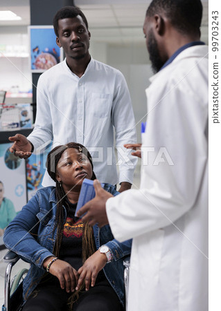 African american woman in wheelchair talking with pharmacist in drugstore, buying prescription treatment, chemist recommending medicaments. Client and pharmacy store consultant, all black team African american woman in wheelchair talking with pharmacist in drugstore, buying prescription treatment, chemist recommending medicaments. Client and pharmacy store consultant, all black team 99703243