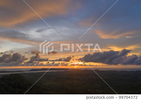 aerial view beautiful yellow sunrise above the mountain in phang Nga valley. slow floating fog blowing cover on the mountain look like as a sea of mist. scenery golden sunrise at horizon background. aerial view beautiful yellow sunrise above the mountain in phang Nga valley. slow floating fog blowing cover on the mountain look like as a sea of mist. scenery golden sunrise at horizon background. 99704372