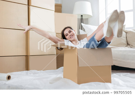 happy young woman unpacking boxes in new apartment happy young woman unpacking boxes in new apartment 99705505