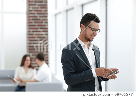 young businessman with smartphone standing near office window. young businessman with smartphone standing near office window. 99705577
