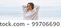 Attractive young woman in white hoodie walking along the seashore early morning 99706690