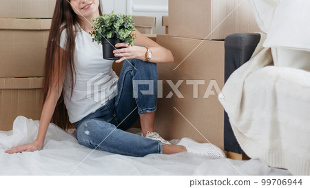 young woman with a home plant sitting on the floor in the new l 99706944
