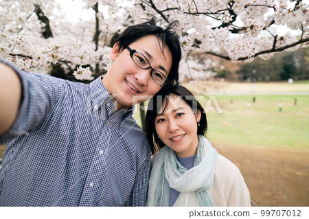 A couple taking a selfie under the cherry blossoms in full bloom A couple taking a selfie under the cherry blossoms in full bloom 99707012