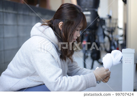 在戶外用毛巾包住水龍頭的女人 在戶外用毛巾包住水龍頭的女人 99707424