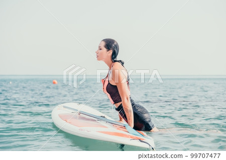 Sea woman sup. Silhouette of happy young woman in pink bikini, surfing on SUP board, confident paddling through water surface. Idyllic sunset. Active lifestyle at sea or river. 99707477