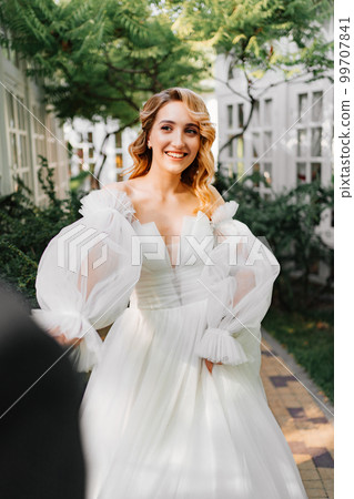 the bride by the hand with the groom walks through the garden. the bride by the hand with the groom walks through the garden. 99707841