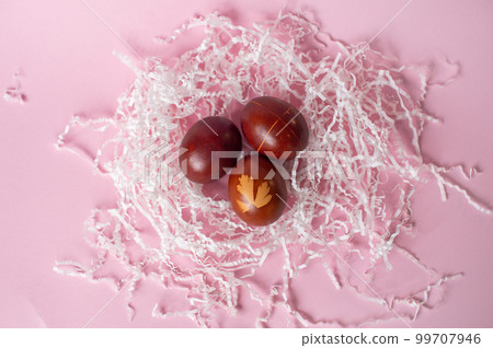 Three framed red eggs with drawings lie in an eco-friendly tray on a pink background 99707946