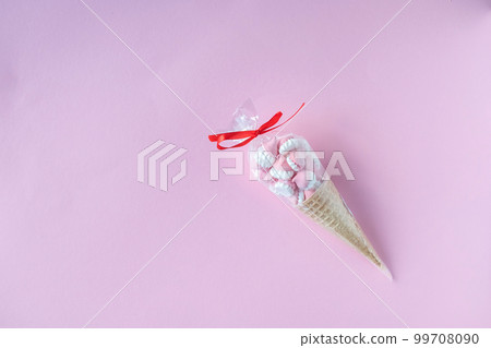 Colorful bright meringues in waffle cookies in transparent packaging lie on a pink background 99708090