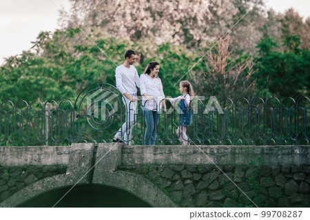 view from afar.parents with their little daughter standing on the bridge. 99708287