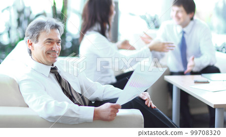 businessman pondering a document sitting in a modern office 99708320