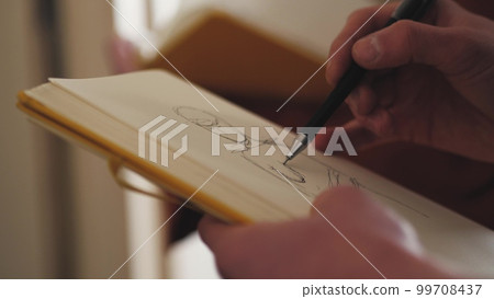 The artist draws a sketch on a piece of paper 99708437