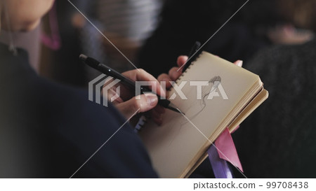 The artist draws a sketch on a piece of paper 99708438