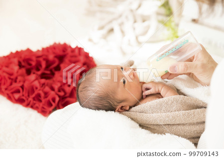 Newborn photo shoot Mother giving milk and baby drinking it 99709143