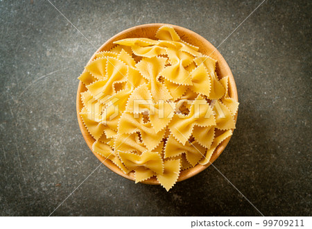 Dry uncooked farfalle pasta in bowl Dry uncooked farfalle pasta in bowl 99709211