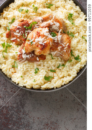 Traditional Italian dish Risotto with chicken, garlic, parmesan cheese and herbs closeup on the plate. Vertical top view 99711039