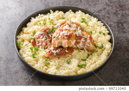 Homemade creamy rice cooked with white wine, broth, parmesan and garlic served with fried chicken close-up in a plate. Horizontal Homemade creamy rice cooked with white wine, broth, parmesan and garlic served with fried chicken close-up in a plate. Horizontal 99711040