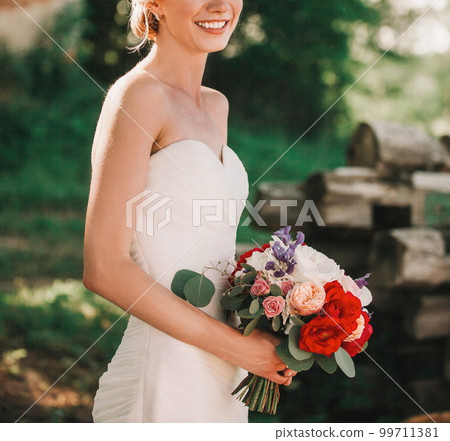 bride with a bouquet of flowers on a blurred background of the Park. 99711381