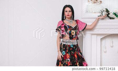 portrait of an attractive young Gypsy woman standing near a decorative fireplace 99711418