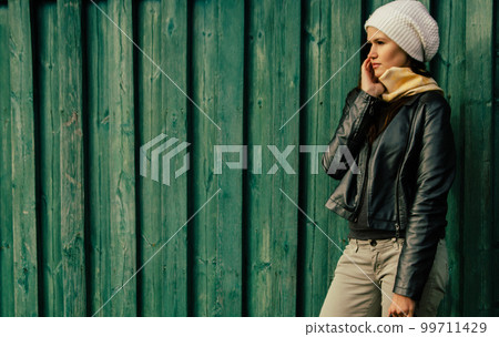 serious young woman standing near wooden fence 99711429