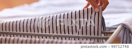Woman hangs clean linen on clothes dryer after washing closeup 99712748