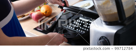 Woman opens Belgian waffle iron to make waffles in kitchen Woman opens Belgian waffle iron to make waffles in kitchen 99712784