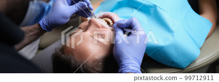 Dentist treats teeth with caries to female patient in dental clinic 99712911
