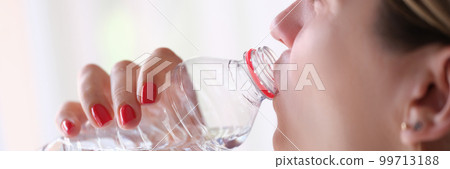 Young woman drinks water from bottle closeup Young woman drinks water from bottle closeup 99713188
