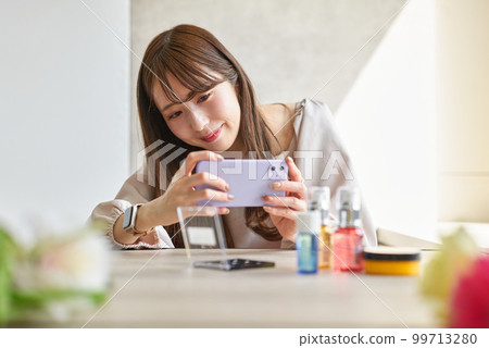 Woman photographing cosmetics with smartphone 99713280