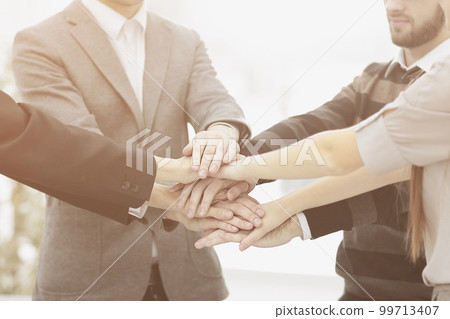 businessman and his business team with hands clasped together to show their unity 99713407
