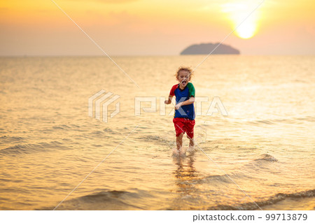 Child playing on ocean beach. Kid at sunset sea. Child playing on ocean beach. Kid at sunset sea. 99713879