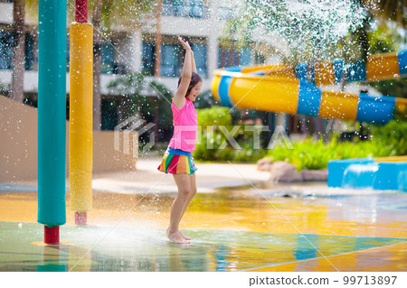 Child playing under tip bucket in water park. Child playing under tip bucket in water park. 99713897